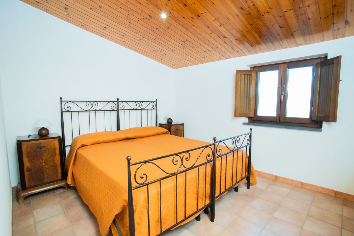 Camera matrimoniale calda e luminosa con soffitto in legno